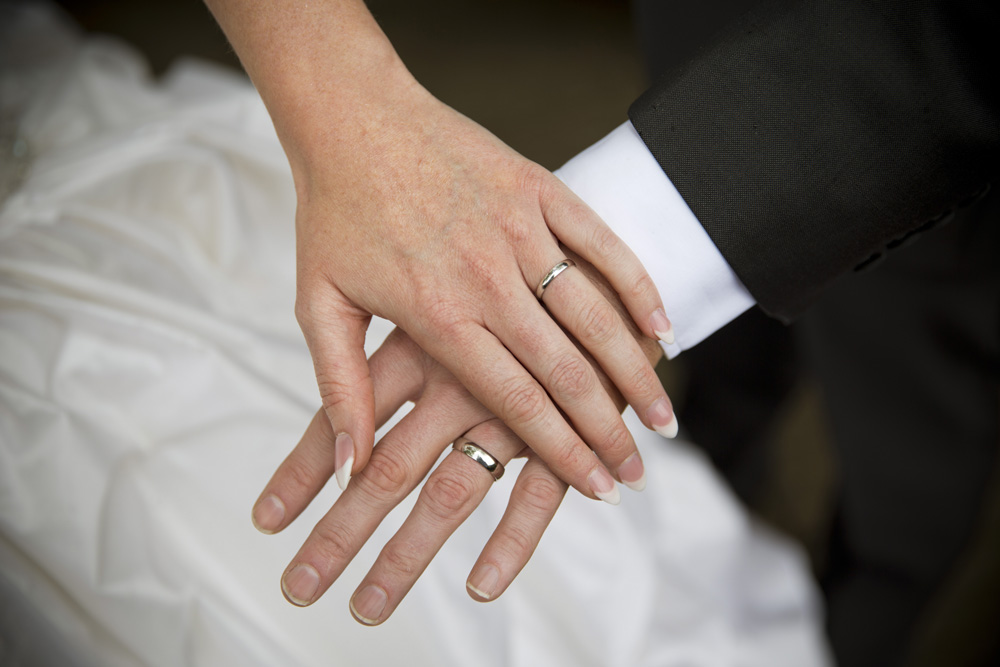 wedding photographer image of bride and groom touching hands showing rings