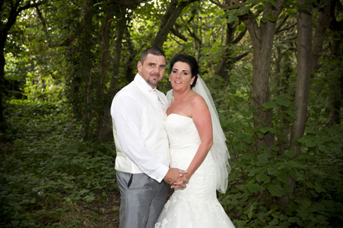 wedding photographer image of bride and groom standing in woodland
