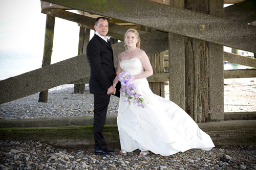 wedding photographer image of bride and groom underneath a beach pier.